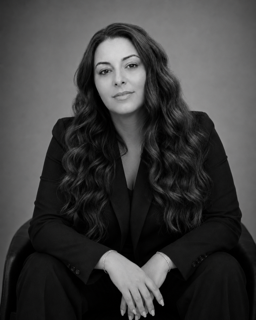 Drea Christine seated in a black blazer for a black-and-white editorial beauty portrait.